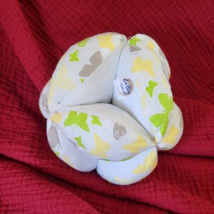 Balle de préhension en tissu Oeko-tex motif papillon vert et jaune et en piquet de coton blanc, le rembourrage est en ouatine spécial peluche. Légère pour être facile à saisir par les mains du tout petit enfant, elle mesure environ 15 cm de diamètre.