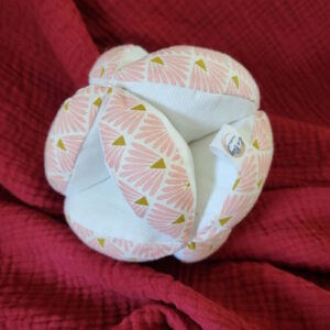 Balle de préhension en tissu Oeko-tex rose et en piquet de coton blanc, le rembourrage est en ouatine spécial peluche. Légère pour être facile à saisir par les mains du tout petit enfant, elle mesure environ 15 cm de diamètre.