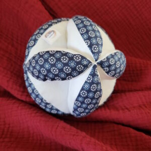 Balle de préhension en tissu Oeko-tex à petits motifs sur fond bleu marine et en piquet de coton blanc, le rembourrage est en ouatine spécial peluche. Légère pour être facile à saisir par les mains de tout petit enfant, elle mesure environ 15 cm de diamètre.