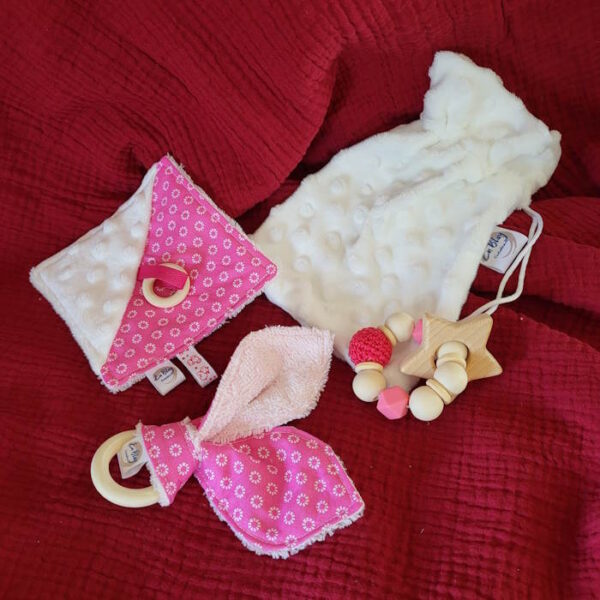 Le sac cadeau de 3 hochets « Rose » de « enblaycreation » est constitué : D’un doudou carré de plusieurs textures Des oreilles de chat en bois et tissu D’un hochet de dentition en perles de silicone et bois qui sera idéal pour aider à soulager les poussées dentaires D’un petit sac en tissu coordonné Assorti à la balle de Préhension « Rose », on retrouve les tissus Oeko-tex : tissu fond rose avec des motifs fleurs blanches, le tissu minky blanc, des perles de silicone alimentaire, perles de coton et du bois non traité.